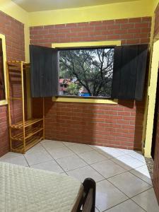 a room with a brick wall and a window at Chalés Moinho in Carrancas
