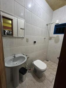 a bathroom with a white toilet and a sink at Chalés Moinho in Carrancas