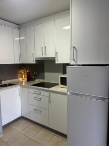a kitchen with white cabinets and a white refrigerator at Apartamento Carles Buïgas in Salou