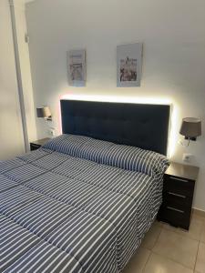 a bedroom with a bed with a blue and white striped bedspread at Apartamento Carles Buïgas in Salou +31 photos