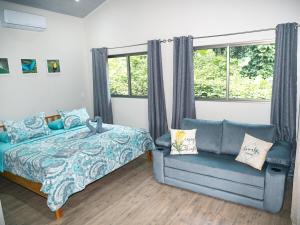 a bedroom with a bed and a couch and a window at Luxury Apartments Nauyaca by Paradiselodge in Platanillo