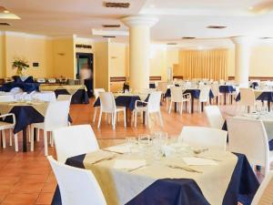 a dining room with white tables and white chairs at Aura Club Porto Rhoca in Squillace