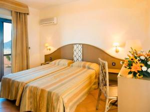 a hotel room with a bed and a vase of flowers at Aura Club Porto Rhoca in Squillace