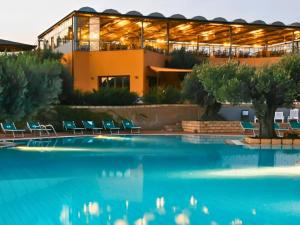 a building with chairs and a pool in front of it at Aura Club Porto Rhoca in Squillace