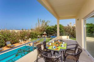 a patio with a table and chairs on a balcony at Villa Aggeliki by Villa Plus in Pírgos Psilonérou