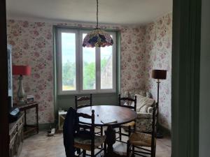 a dining room with a table and chairs and a window at Maison Huitlala in Lavaufranche