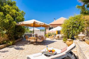 a patio with a table and chairs and an umbrella at Dimitris Cottage in Apergátika