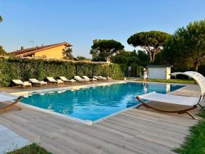 a swimming pool with lounge chairs and a woman standing next to it at Tenuta Fiumara in Marina di Grosseto