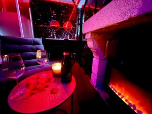 een tafel met twee wijnglazen en een open haard bij Redroom, Spa, Sauna, cheminée, romantique pour 2 in Quimperlé