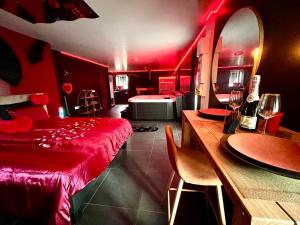 een rode kamer met een bed en een tafel met wijnglazen bij Redroom, Spa, Sauna, cheminée, romantique pour 2 in Quimperlé