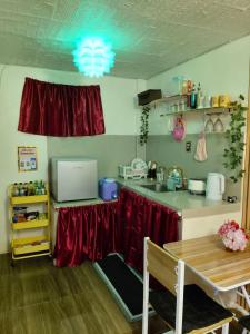 een keuken met een aanrecht met rode gordijnen en een tafel bij Ciel's Haven Free Breakfast in Binangonan