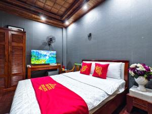 a bedroom with a bed with red pillows and a tv at Xumi Motel in Hanoi