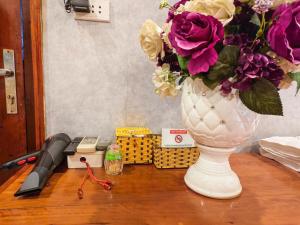 a white vase with flowers in it on a table at Xumi Motel in Hanoi +11 photos