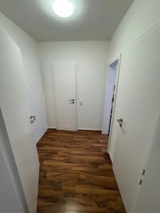 un corridoio vuoto con pareti bianche e pavimenti in legno di Apartment a Gelsenkirchen