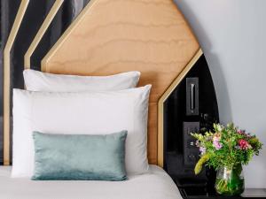 un letto con testiera e un vaso con fiori di The 1932 Hotel & Spa Cap d'Antibes - MGallery Collection a Juan-les-Pins