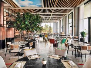 a restaurant with tables and chairs in a room with windows at Mövenpick Resort Al Marjan Island in Ras al Khaimah