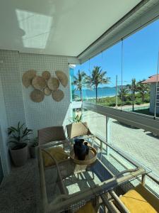 a balcony with a table and chairs and a view of the ocean at 4 ILHAS, 2 SUITES, 2 GARAGENS in Bombinhas