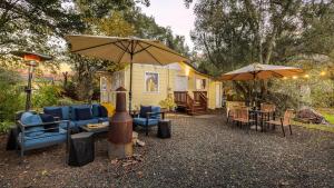 une terrasse avec des chaises, des tables et un parasol dans l'établissement Grapevine Cottage by AvantStay Hobby Vineyard Firepit, à Glen Ellen