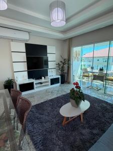 a living room with a television and a table with a plant at 4 ILHAS, 2 SUITES, 2 GARAGENS in Bombinhas