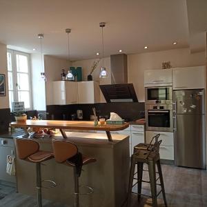 a kitchen with a counter and some stools in it at Mon Jardin Secret in Maligny