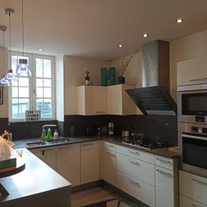 a kitchen with white cabinets and a stove top oven at Mon Jardin Secret in Maligny +3 photos