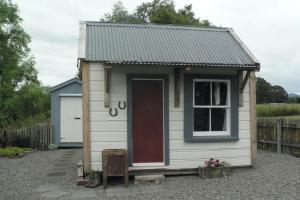 un petit hangar blanc avec une porte rouge dans l'établissement The Old Shepherd, à Masterton