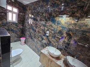 a bathroom with two toilets and a sink and a shower at HOTEL REAL Inn in Muzaffarpur