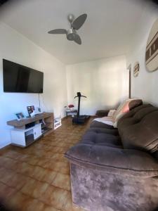 a living room with a couch and a flat screen tv at Casa com piscina em Peruíbe in Peruíbe