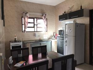 a kitchen with a table and a white refrigerator at Casa com piscina em Peruíbe in Peruíbe