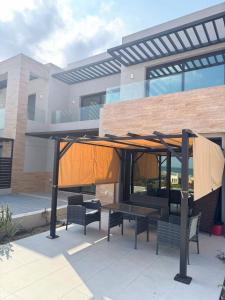 een paviljoen met een tafel en banken voor een gebouw bij The Beach House by JS in Muscat