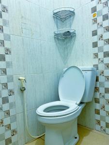 a bathroom with a toilet with a basket on the wall at Bandung CoStay in Bandung