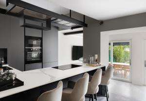a kitchen with a white counter and chairs at Maison MUSA at Ca' Bela in Sala Comacina