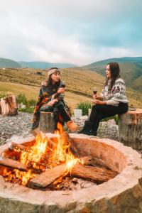 due persone sedute intorno al fuoco con bicchieri di vino di Solarium Cabaña a Riobamba