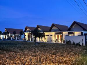 a large white house with a tree in a field at Svadarma Bali Villa in Darmasaba