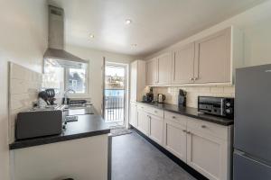a kitchen with white cabinets and black counter tops at Mayflower Penthouse in Dartmouth