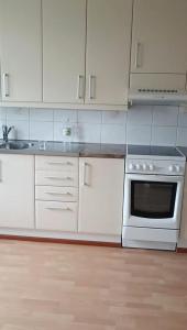 een keuken met witte kasten en een kookplaat oven bij Simple Cozy House in Raahe