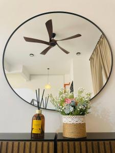 a large mirror on a wall with flowers on a table at Che Nat Che Nor Homestay in Kuala Terengganu