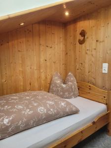 a bed in a room with a wooden wall at Haus Steinacher in Hopferau