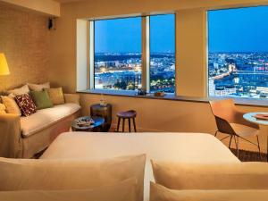 un soggiorno con un divano e una grande finestra di Too Hotel & Spa Paris - MGallery Collection a Parigi