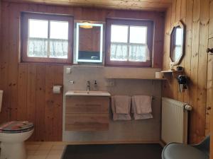 a bathroom with a sink and a toilet and two windows at Haus Steinacher in Hopferau