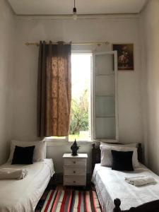 two beds in a room with a window at Pension Gibraltar in Tangier