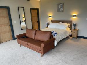 a bedroom with a bed and a leather couch at Spring Meadow in Durham +5 photos