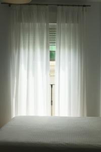 a bedroom with a bed and a window with white curtains at Apartamentos Océanos in Málaga