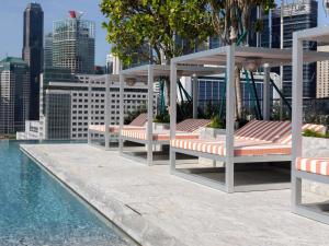 een groep banken naast een zwembad bij Mondrian Singapore Duxton in Singapore