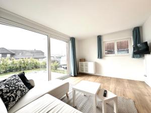 een woonkamer met een witte bank en een groot raam bij Furnished Living Room in Günsberg Solothurn in Günsberg  