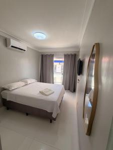een witte kamer met een bed en een spiegel bij Isadora Pousada in Salinópolis +9 foto's