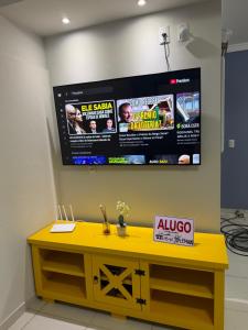 een gele tafel met een grote televisie aan de muur bij Mariscal 2 quartos 3 banheiros -SOBRADO AMENDOEIRA in Bombinhas