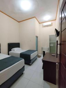 ein Hotelzimmer mit zwei Betten und einem Schreibtisch in der Unterkunft Victoria Homestay in Pulau Lutung + 1 Foto