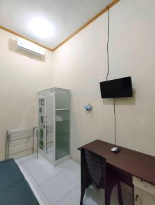 ein Zimmer mit einem Schreibtisch und einem Fernseher an der Wand in der Unterkunft Victoria Homestay in Pulau Lutung