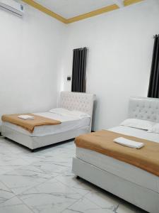 zwei Betten nebeneinander in einem Zimmer in der Unterkunft Victoria Homestay in Pulau Lutung